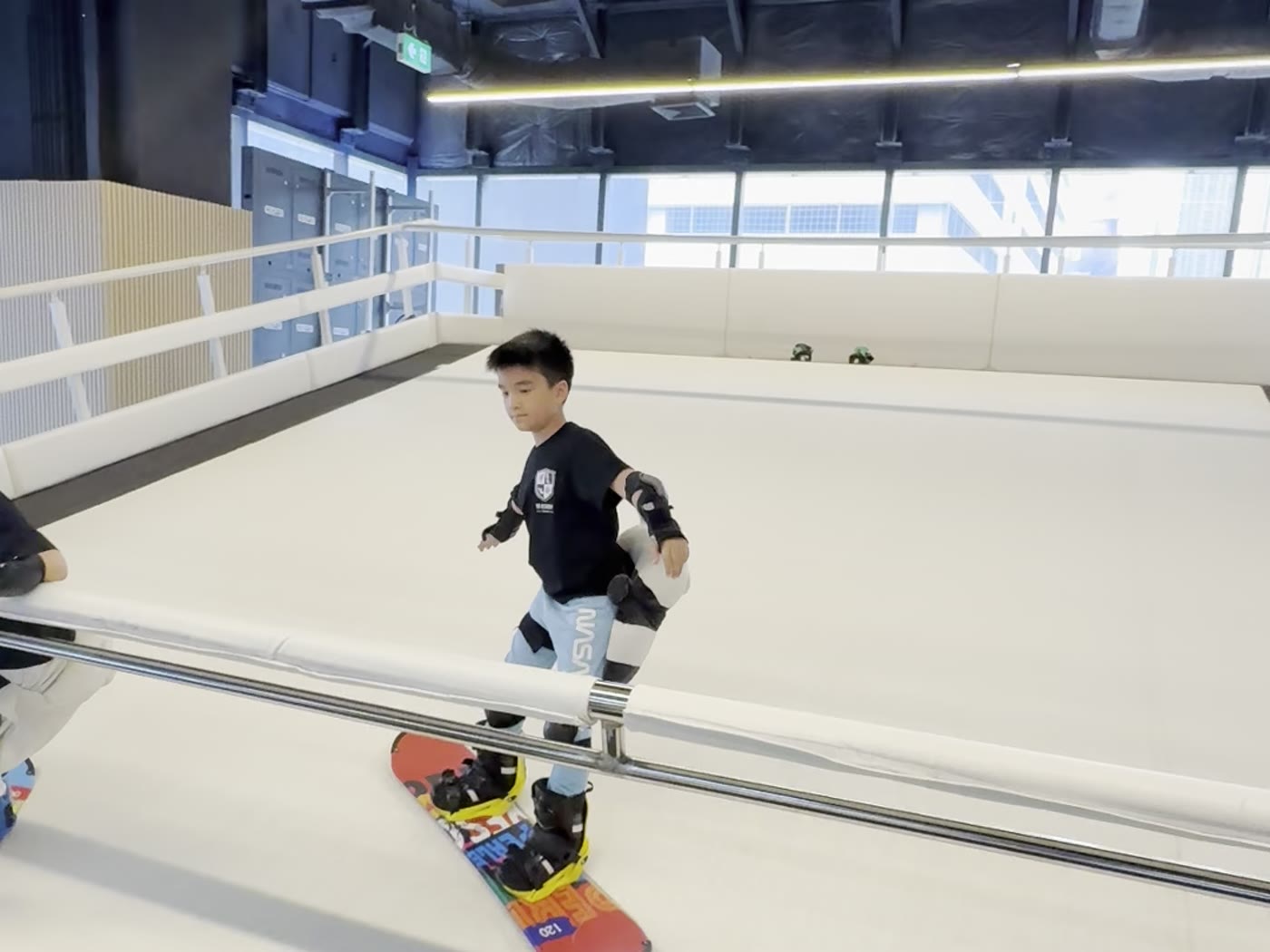 A child snowboarding on the moving slope at SKI Academy Thailand