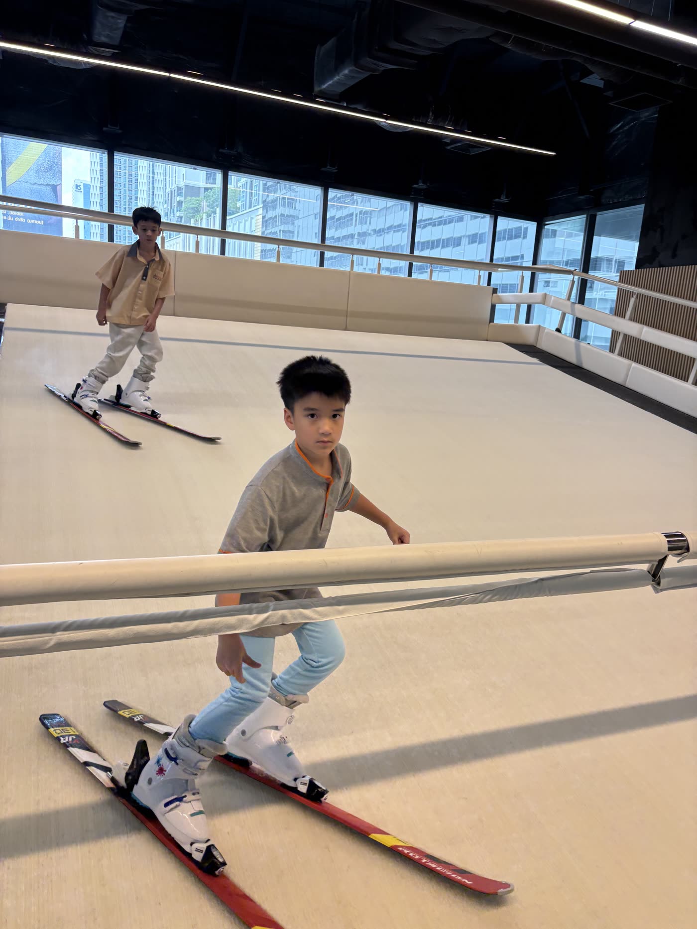 Two children skiing on the moving slope at SKI Academy Thailand